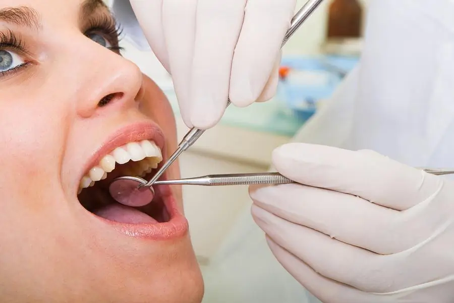 Dentist performing early dental exam on adult patient